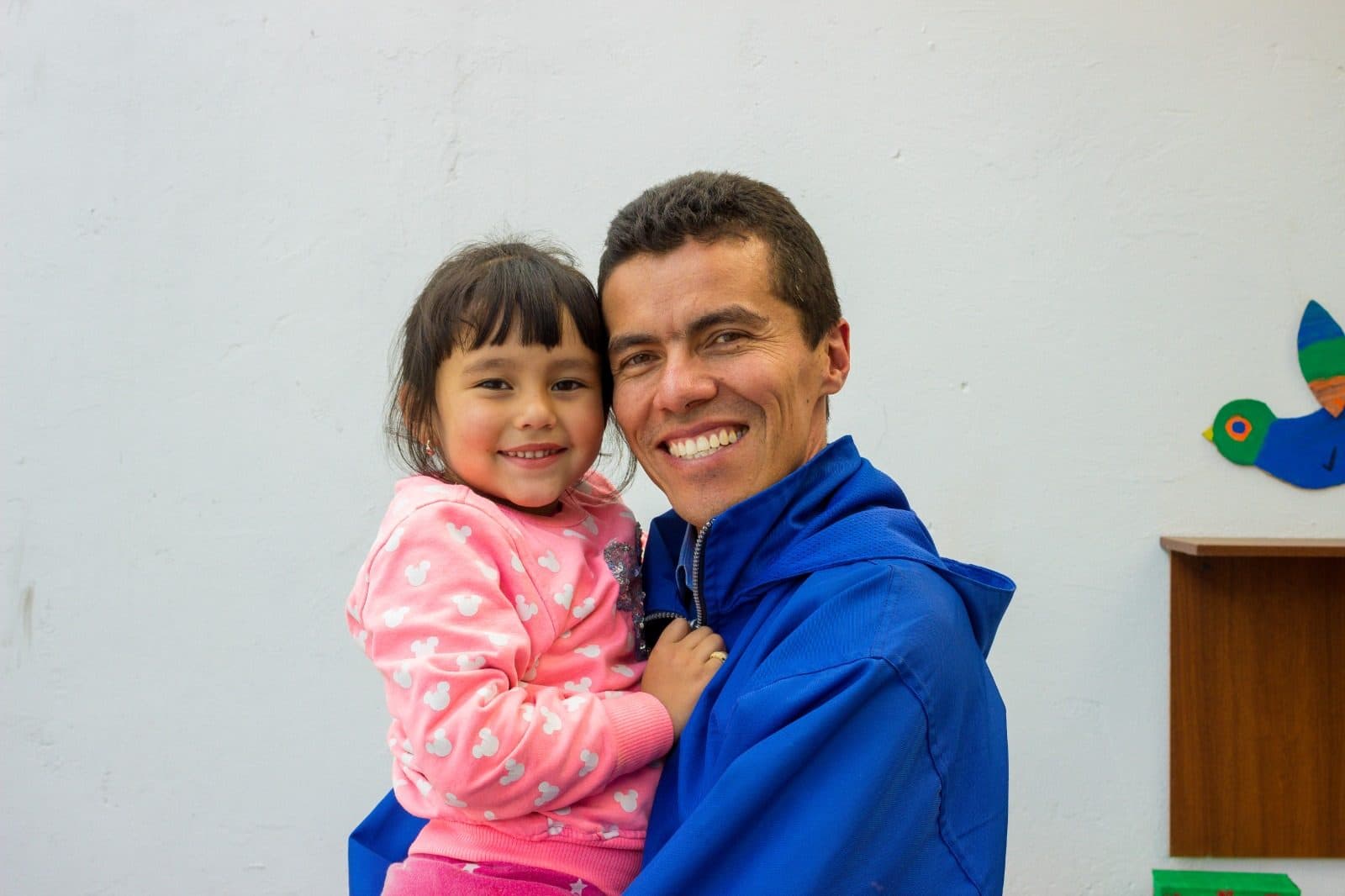 Educador de la Fundación Buena Semilla cargando a una niña de la Casa