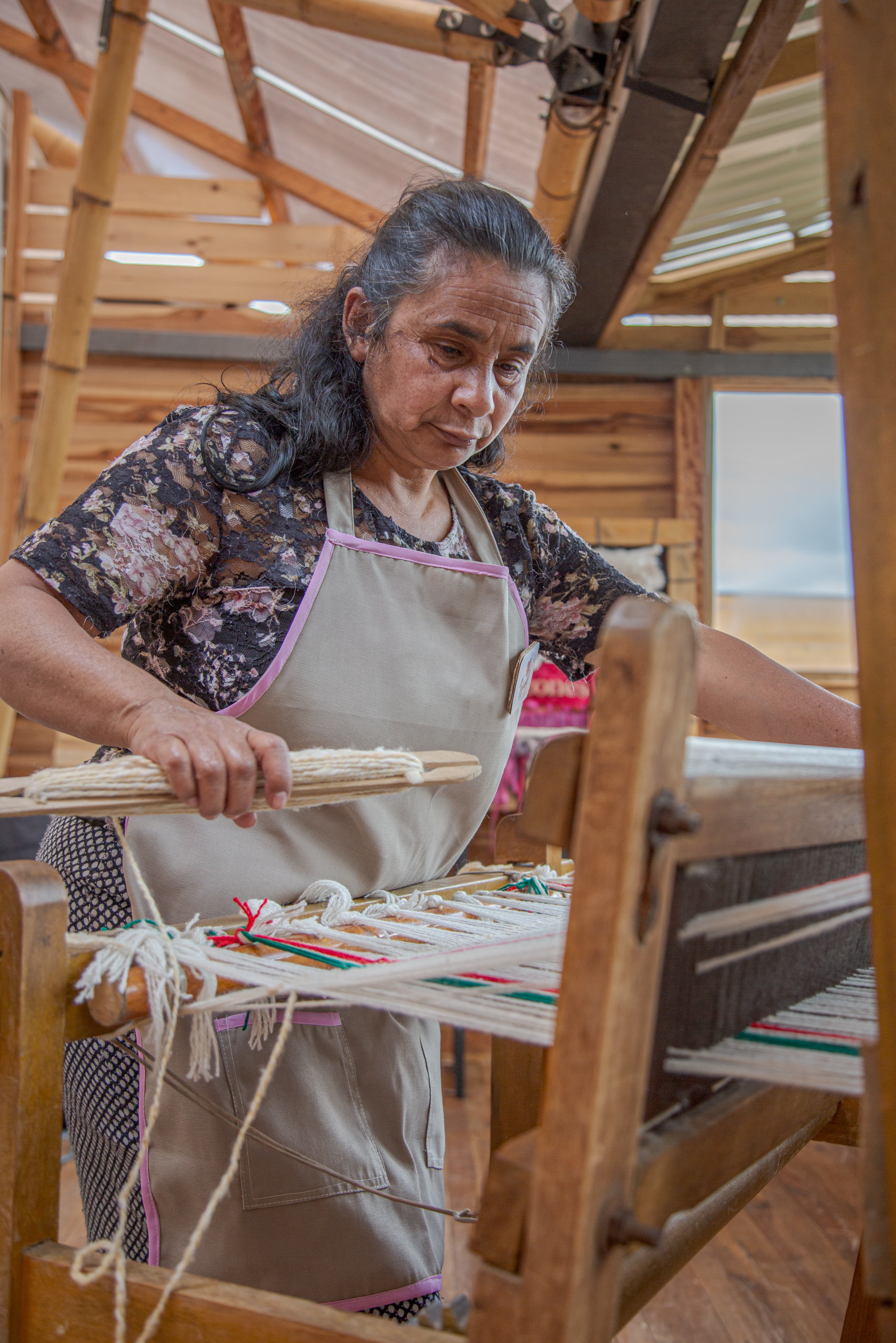Mujer tejiendo en telar manual en el taller Tejiendo Corazones